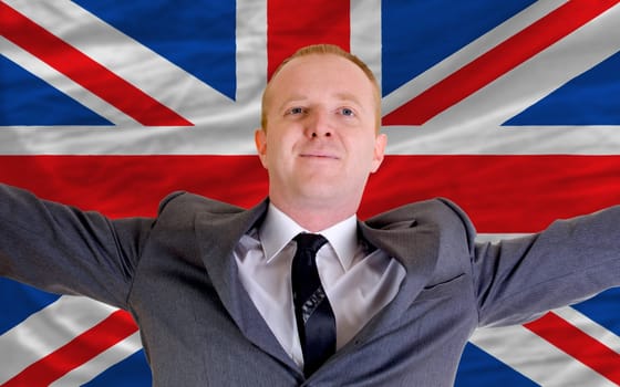 joyful investor spreading arms after good business investment in united kingdom, in front of flag