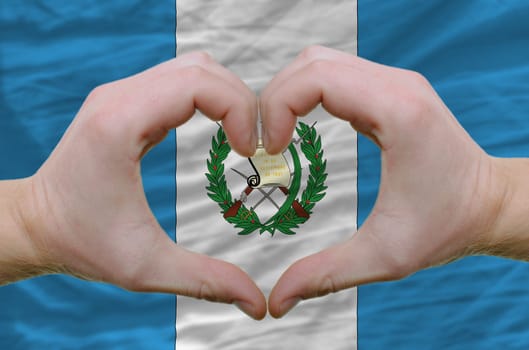 Gesture made by hands showing symbol of heart and love over guatemala flag