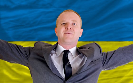 joyful investor spreading arms after good business investment in ukraine, in front of flag