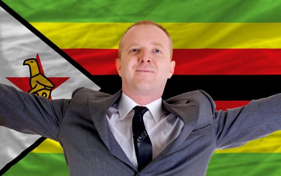 joyful investor spreading arms after good business investment in zimbabwe, in front of flag