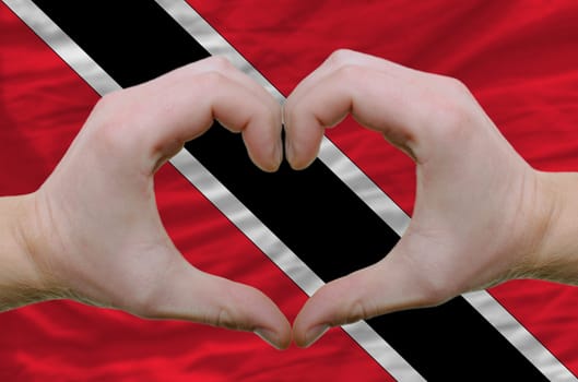 Gesture made by hands showing symbol of heart and love over trinidad and tobaog flag