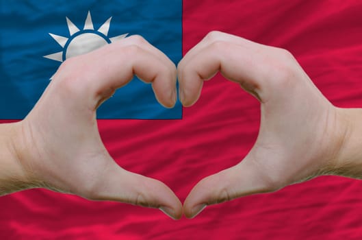 Gesture made by hands showing symbol of heart and love over taiwan flag