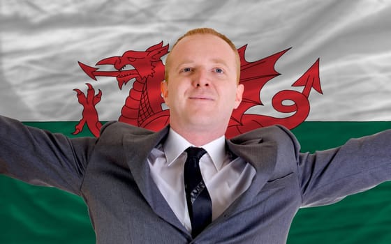 joyful investor spreading arms after good business investment in wales, in front of flag