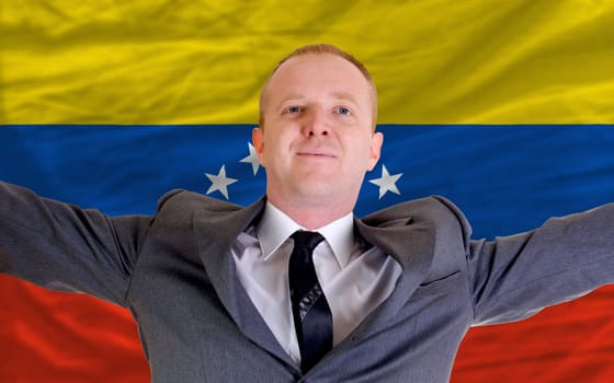 joyful investor spreading arms after good business investment in venezuela, in front of flag