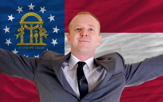 joyful investor spreading arms after good business investment in georgia, in front of flag