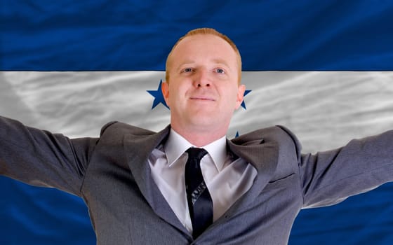 joyful investor spreading arms after good business investment in honduras, in front of flag