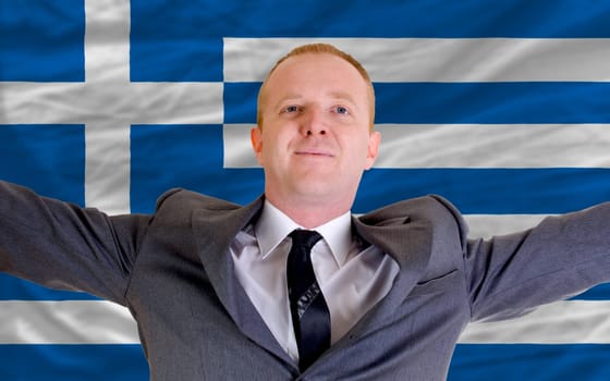 joyful investor spreading arms after good business investment in greece, in front of flag