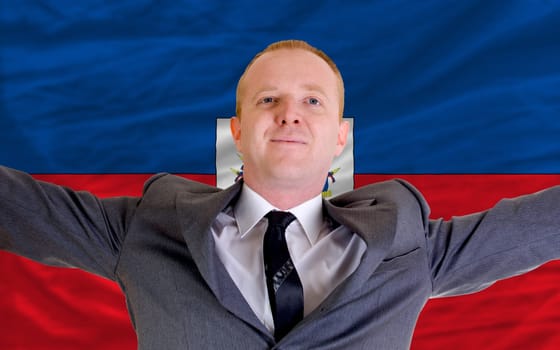 joyful investor spreading arms after good business investment in haiti, in front of flag