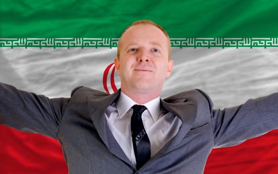 joyful investor spreading arms after good business investment in iran, in front of flag