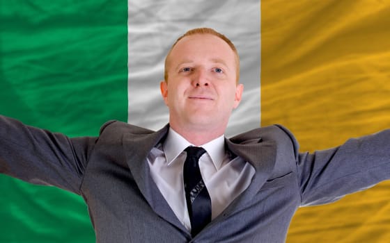 joyful investor spreading arms after good business investment in ireland, in front of flag