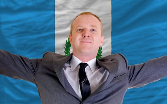 joyful investor spreading arms after good business investment in guatemala, in front of flag