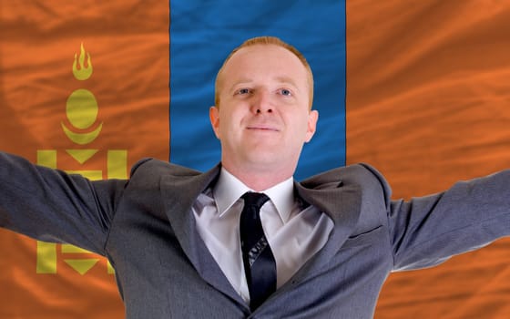 joyful investor spreading arms after good business investment in mongolia, in front of flag