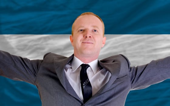 joyful investor spreading arms after good business investment in el salvador, in front of flag