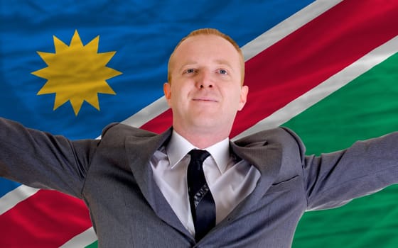 joyful investor spreading arms after good business investment in namibia, in front of flag