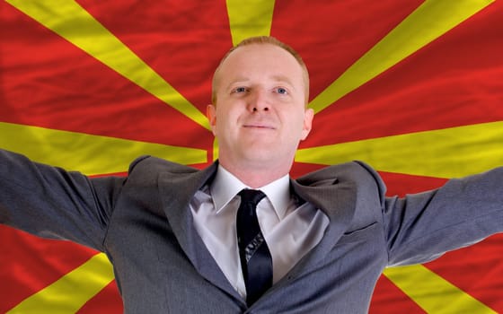 joyful investor spreading arms after good business investment in macedonia, in front of flag