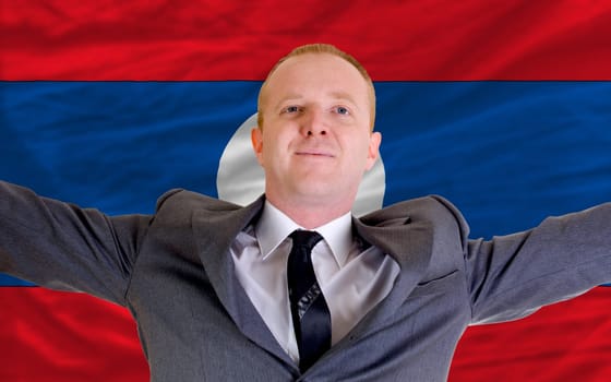 joyful investor spreading arms after good business investment in laos, in front of flag