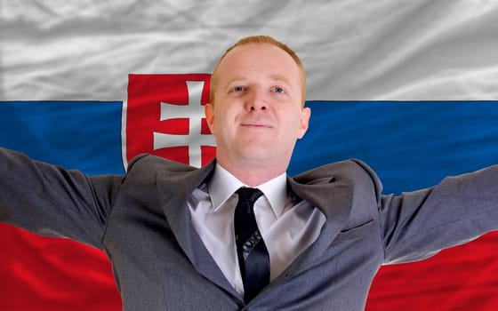 joyful investor spreading arms after good business investment in slovakia, in front of flag