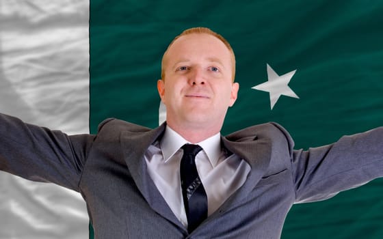 joyful investor spreading arms after good business investment in pakistan, in front of flag