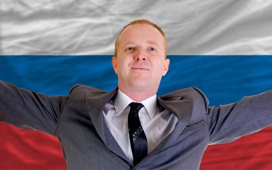 joyful investor spreading arms after good business investment in russia, in front of flag