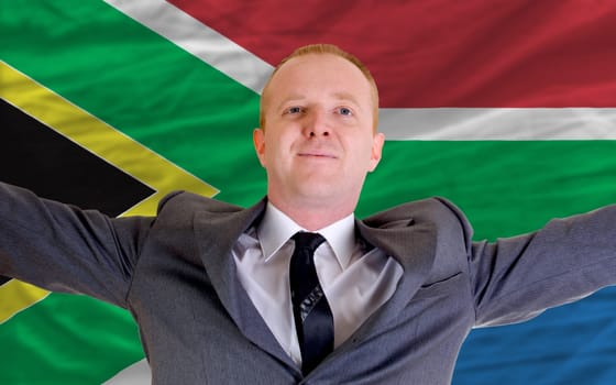 joyful investor spreading arms after good business investment in south africa, in front of flag