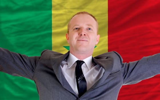 joyful investor spreading arms after good business investment in senegal, in front of flag