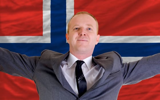 joyful investor spreading arms after good business investment in norway, in front of flag