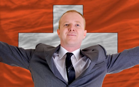 joyful investor spreading arms after good business investment in swiss, in front of flag