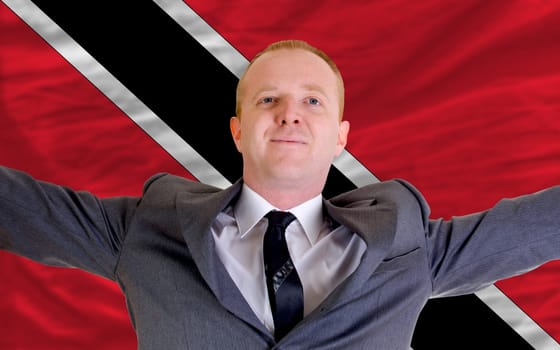 joyful investor spreading arms after good business investment in trinidad tobago, in front of flag