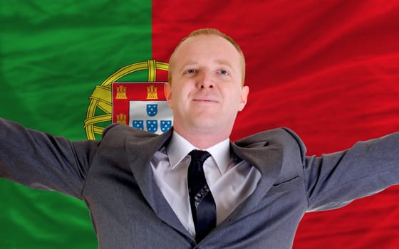 joyful investor spreading arms after good business investment in portugal, in front of flag