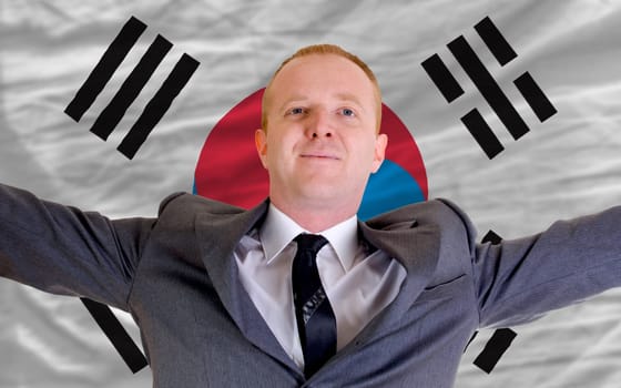 joyful investor spreading arms after good business investment in south korea, in front of flag