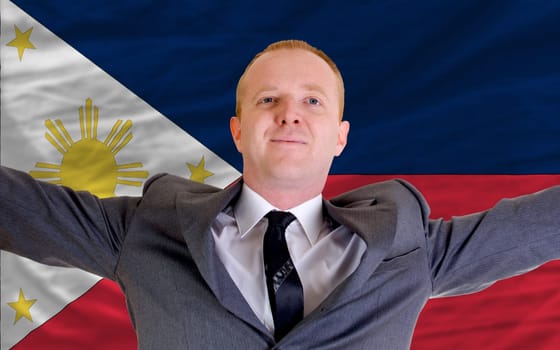 joyful investor spreading arms after good business investment in phillipines, in front of flag