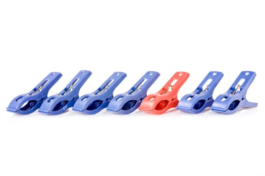 Clothes pegs are in a row. Blue ones and one red