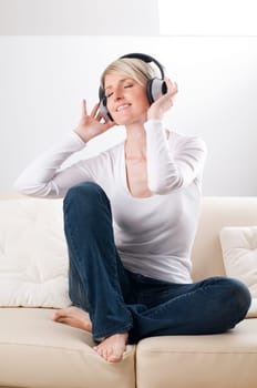 Young blond woman listening music on headphones