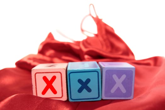 xxx written with blocks on a silk nightie against white background