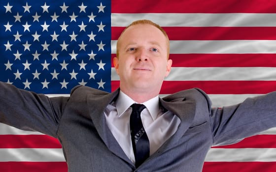 joyful investor spreading arms after good business investment in america, in front of flag