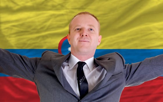 joyful investor spreading arms after good business investment in columbia, in front of flag
