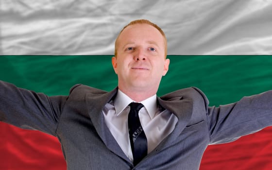 joyful investor spreading arms after good business investment in bulgaria, in front of flag