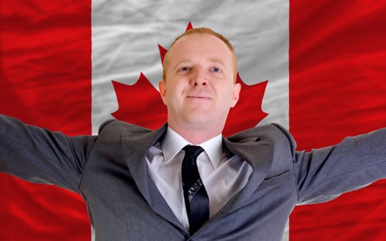joyful investor spreading arms after good business investment in canada, in front of flag