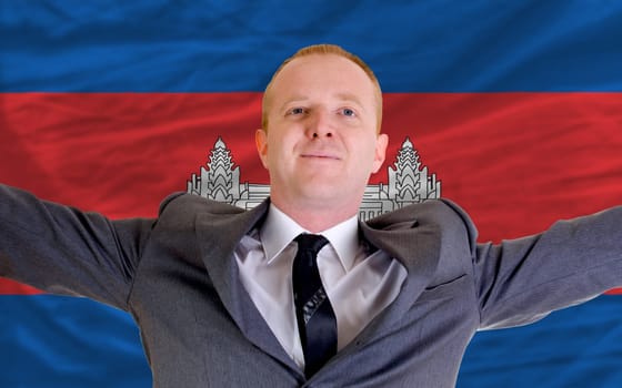 joyful investor spreading arms after good business investment in cambodia, in front of flag
