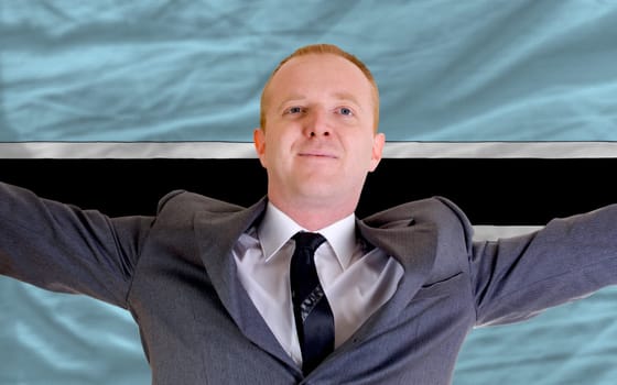 joyful investor spreading arms after good business investment in botswana, in front of flag