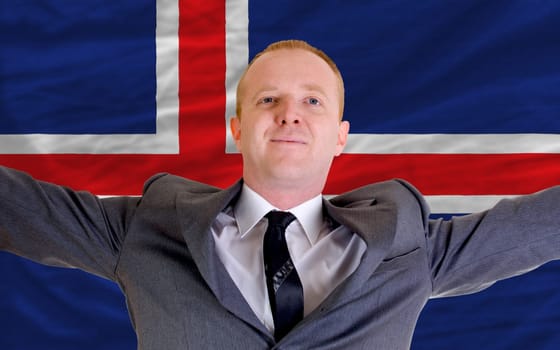 joyful investor spreading arms after good business investment in iceland, in front of flag