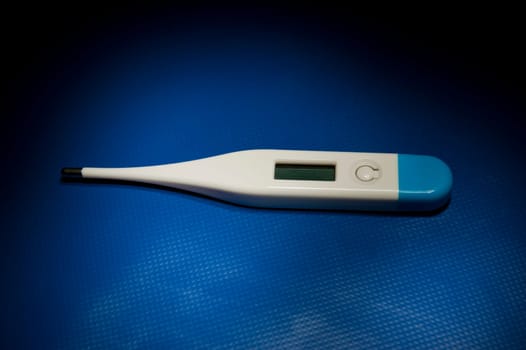Isolated colored thermometer laying on blue studio table