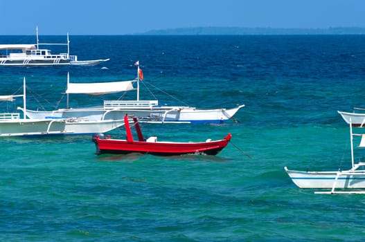 red motorboat together with many traditional philippine bangkas