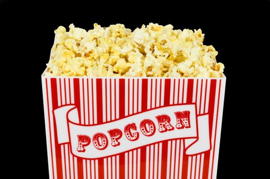 A container of popped popcorn isolated on a black background
