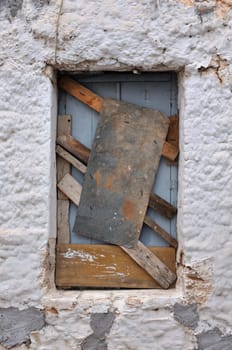 Boarded up window frame of an old house and rough wall background texture.