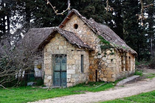 Derelict rural house with crumbling roof and dirt road in the woods.