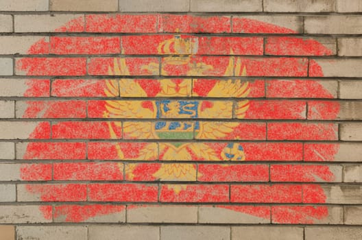 Chalky montenegrian flag painted with color chalk on grunge old brick wall