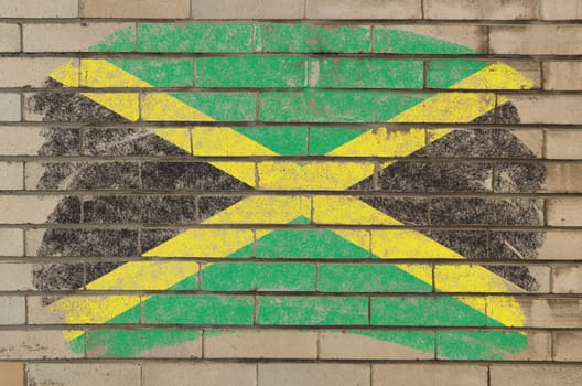 Chalky jamaican flag painted with color chalk on grunge old brick wall