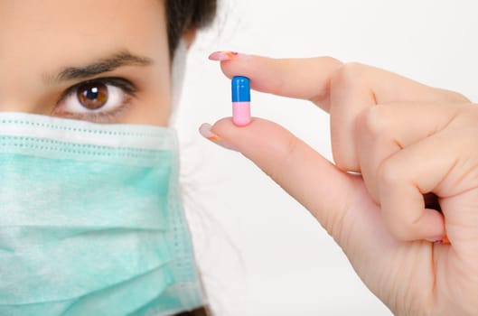 Blue pink pill in a woman&#039 s hand, isolated an a white background