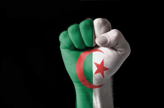 Low key picture of a fist painted in colors of algeria flag